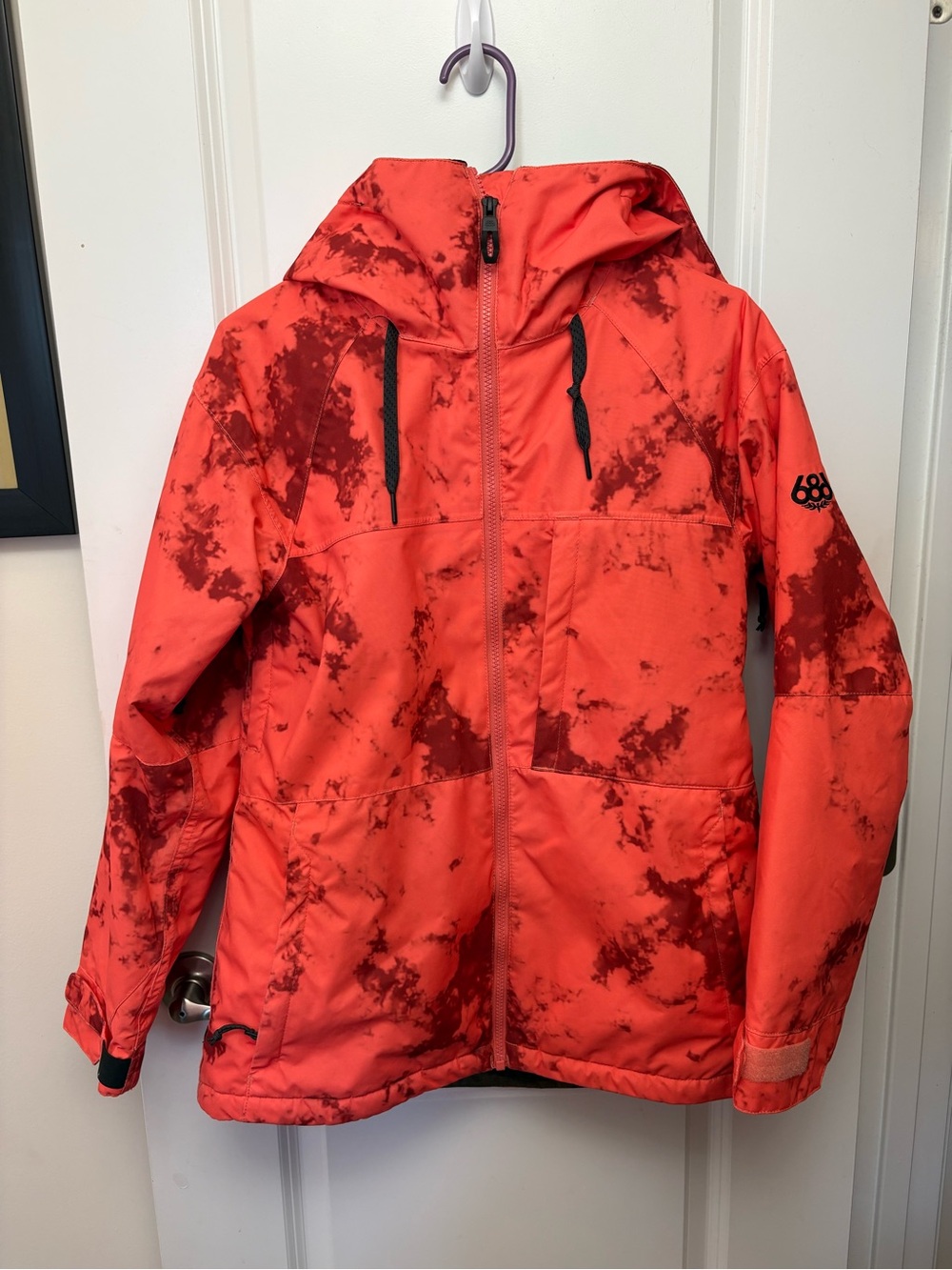 686 women’s orange, tie-dye snowboard jacket.